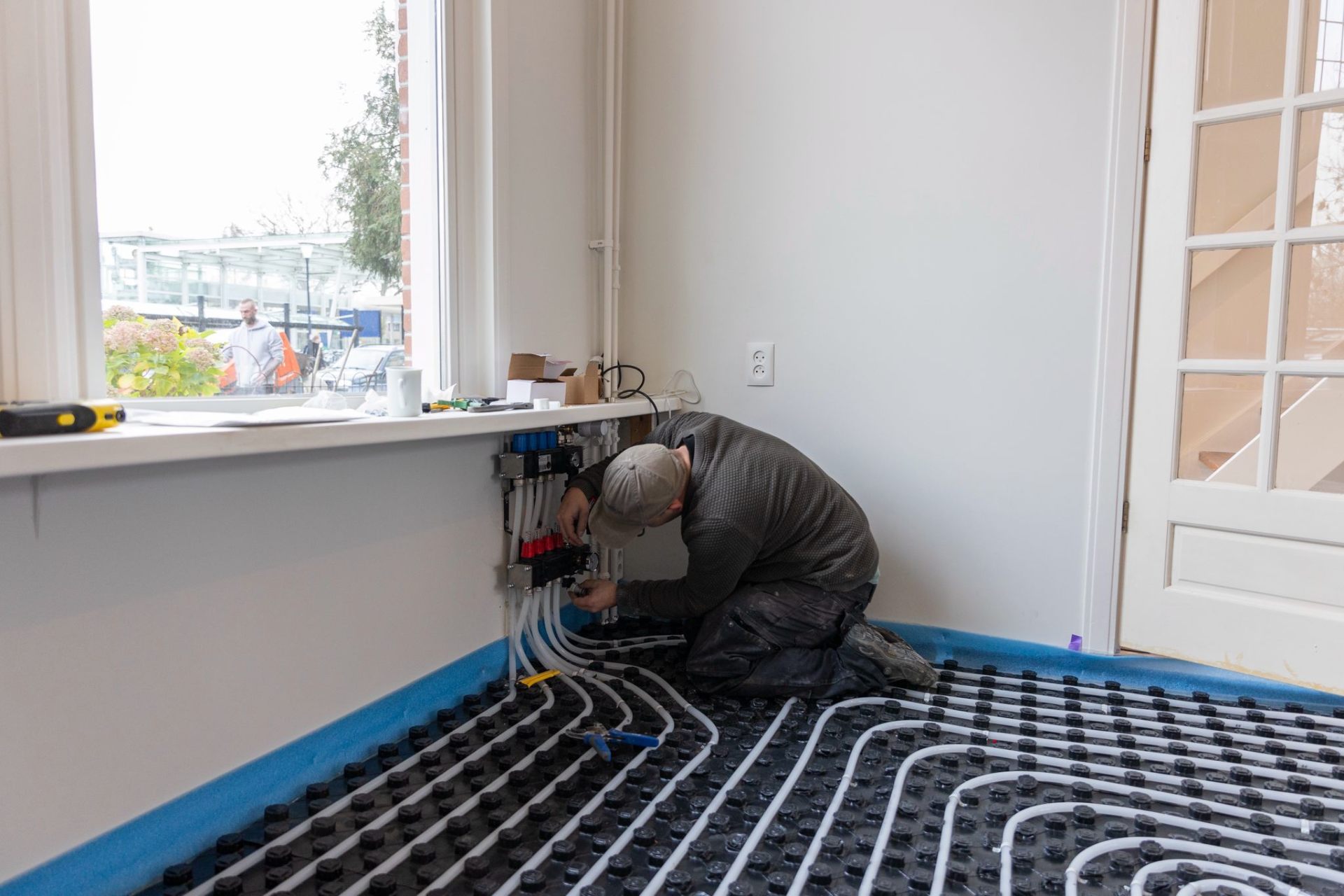 Installateur legt vloerverwarmingsleidingen op een uitgeharde Isopact ondervloer als voorbereiding op de afwerkvloer